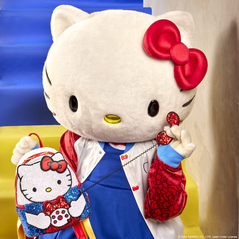 Hello Kitty wearing a blue top and the Loungefly Hello Kitty 50th Anniversary Souvenir Jacket holding the Loungefly Sanrio Exclusive Hello Kitty 50th Anniversary Phone Sequin Cosplay Mini Backpack and holding the sequin phone to her ear 